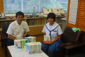 児童文学作家、山中さんから寄贈された児童文学書を喜ぶ国仲校長（左）と生徒会長の洲鎌さん＝24日、来間小中学校