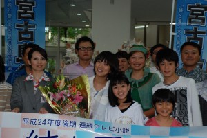 花束を手に出演者や関係者らと記念撮影に臨んだ夏菜さん＝１２日、宮古空港