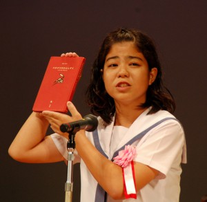 感銘を受けた物語「ハチドリのひとしずく」を掲げ、表現豊かに発表を行った砂川さん＝２６日、豊見城市中央公民館