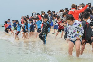子どもたちは一斉に海に走り込み初泳ぎを楽しんだ＝７日、与那覇前浜ビーチ