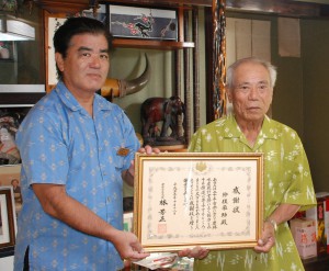 大城センター長（左）から狩俣さんに大臣感謝状が伝達された＝18日、上野新里（高田）の狩俣さん宅