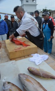 生魚を使って活け締めを披露する上田さん＝20日、池間漁協前