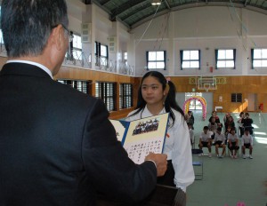 職員手作りのアルバムを受け取った邊土名さん＝２４日、宮島小学校体育館
