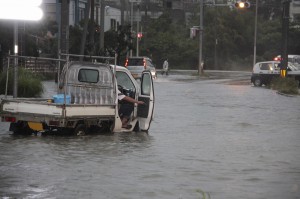 水がたまった道路で立ち往生する車両。しばらくして警察官と市民の力を借りて脱出した＝１０日午後５時すぎ、平良東仲宗根の市道