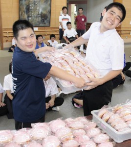 初給料で母校にパン１６０個をプレゼントした平良君（左）。右は生徒を代表して受け取った沼田貴吉君＝２１日、宮古特別支援学校