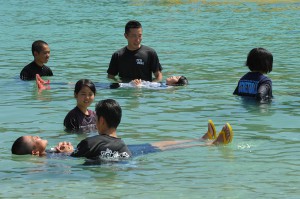 海保職員の指導で、空のペットボトルを使用して海面に浮かぶ訓練をする生徒ら＝２２日、インギャーマリンガーデン