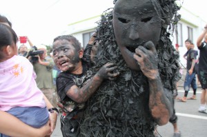 パーントゥに抱きかかえられおびえた顔で周囲に助けを求める子供＝１１日、平良島尻