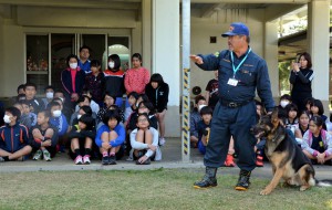 災害救助犬の実演にくぎ付け。犬に寄り添う幸喜さん＝３日、下地小学校