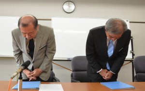 会見で担当職員２人に対する処分内容を発表し、市民に対して頭を下げる長濱副市長（左）と村吉順栄総務部長＝30日、市役所平良庁舎