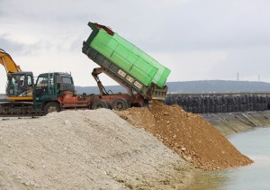 積載した土砂を埋め立て現場に下ろすダンプカー＝２５日、平良港・漲水地区