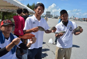 大物チカメキントキを釣り上げた新里共同代表（左）と宮総実釣部の生徒たち＝２３日、市内の荷川取漁港