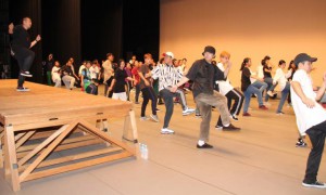 エンディングで踊るダンスの指導をインストラクターから受ける参加者＝23日、マティダ市民劇場