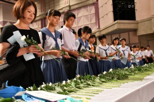 参列した生徒たちが献花でみ霊を慰めた＝２３日、マティダ市民劇場