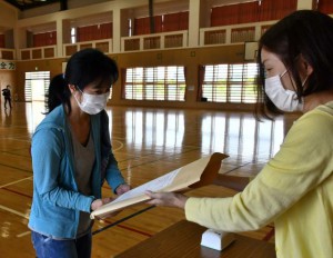 教科書などを受け取る保護者＝16日、久松小体育館