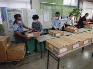 特別定額給付金申請書が入った段ボール箱を郵便局員に手渡す市職員ら＝22日、市新型コロナウイルス対策給付支援室