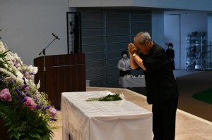 献花を行う城辺地域遺族会の藤本栄一会長＝23日、ＪＴＡドーム宮古島