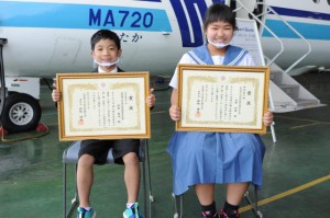 第21回未来に残そう青い海・海上保安庁図画コンクール表彰式に出席した（左から）西辺小２年の安里基冶君と西辺中１年の上原美春さん＝22日、那覇航空基地