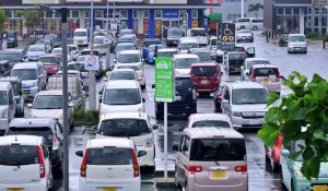 観光客の多さを物語るように、地元の買い物客の車に加え、多くのレンタカーで混み合った＝12日、市内の大型スーパーの駐車場