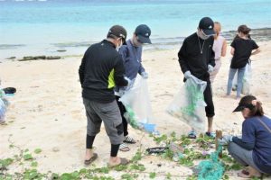 ビーチに落ちているごみを拾い集める参加者＝24日、新城海岸