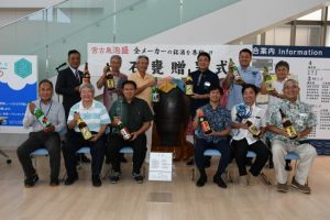 泡盛一石がめ贈呈式でかめに泡盛を注ぎ入れた参加者=19日、市役所