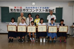 最優秀賞を受賞した砂川君(前列左から3人目)、宮里さん(同4人目)ら受賞者(前列)と関係者たち=22日、平良地方合同庁舎