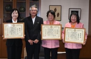座喜味市長（左から２人目）から賞状を受け取った仲村さん（左）、伊志嶺さん（右から２人目）、洲鎌さん＝29日、市役所