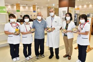 同病院の職員が見守る中、平良代表から本永院長にちらしずしが贈られた＝１日、宮古病院