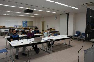 モニターを見ながら取り組み事例について報告を聞く市環境衛生課の職員ら＝９日、市クリーンセンター会議室