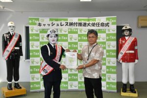 粟國署長（右）から宮古島まもる君に任命書が手渡された＝11日、宮古島税務署