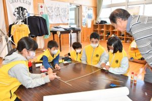 砂川さんから指導を受けながら、たこ作りに取り組む児童たち＝19日、ティダっ子学園
