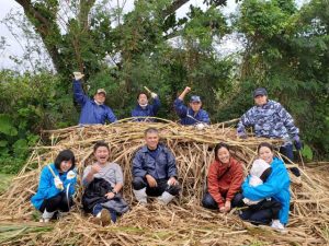 島外からの来島者がキビ刈り体験を行った＝４日、字塩川の清村隆男さんのほ場