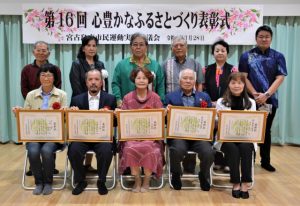 表彰された（左から）川満恵美子さん、仲間会長、池間代表、砂川さん、岸本さんと関係者の皆さん＝28日、市保健センター多目的ホール