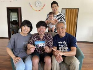 サタパンビンを手に島尻さん夫妻との再会を喜ぶ中川さん（中央）＝14日、平良狩俣