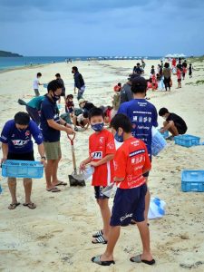 約１００人の参加者が流れ着いた軽石を除去した＝16日、前浜ビーチ