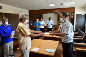 下地本部長（手前右）が要請書を座喜味市長（同左）に手渡した＝22日、市役所
