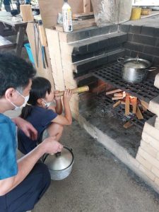 「火吹き竹」を使って火力を上げることに挑戦する親子＝28日、宮古青少年の家