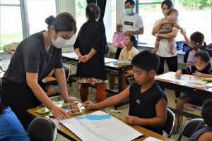 伊良部さん（左）が児童たちの絵について指導した＝16日、市上野公民館