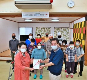 親の会の本永会長（手前左）から新しい大型エアコンが寄贈され、喜ぶ利用者ら＝25日、みやこ学園