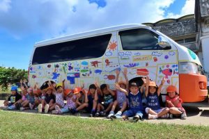 ３園の園児たちが「ＳＤＧｓ」をテーマに地域の自然を大切にすることを願うメッセージを送迎車に描いた＝26日、城辺幼稚園