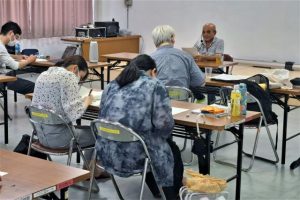渡真利さん（奥）が学生たちに宮古方言を紹介した＝７日、宮古教育会館