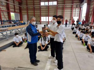 生徒代表が勝連支店長（手前左）に鉄筋ラックを贈呈した＝６日、那覇鋼材宮古機材センター