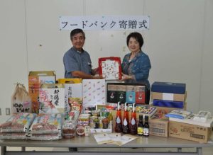 食料品を手渡す上地さん（右）＝７日、沖縄宮古法人会