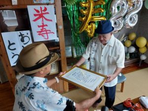 仲間会長（右）から表彰状が川満さんに手渡されたほか、自治会役員が高齢者宅を１軒１軒訪ねて長寿の先輩を敬った＝19日、池間島
