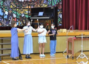 児童にマリンバのたたき方を指導する「くまから」のメンバー＝２日、狩俣小学校