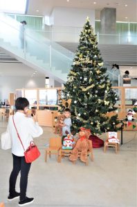クリスマスツリーをバックに写真撮影をする親子＝26日、市立図書館