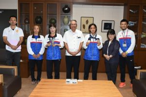 座喜味市長（中央）にメダル獲得を報告した伊良波さん（左から３人目）、丸山さん（右から３人目）と関係者＝16日、市役所