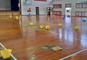平良第一小学校の体育館では雨の日には天井からの雨漏りの水を受けるためのバケツが多数設置される（11月撮影、読者提供）