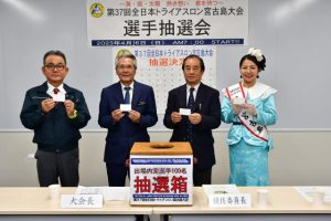 抽選カードを手にする（左から）伊川実行委員長、座喜味大会長、砂川競技委員長、山里さん＝16日、市役所
