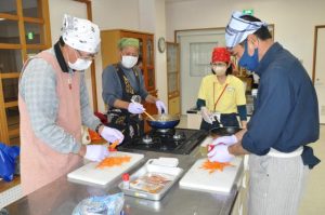 豚肉のしょうが焼きなどに挑戦する男性たち＝20日、下地公民館