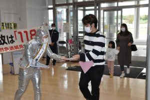 訪れた市民らに「118番」の正しい利用を呼び掛けるゲラゲラ星人(左)=18日、市役所